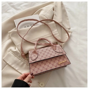 Détail d'un sac à bandoulière vintage avec plaque logo dorée sur un blazer beige