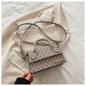 Détail d'un sac bandoulière vintage à motif carreaux sur un blazer beige avec logo doré