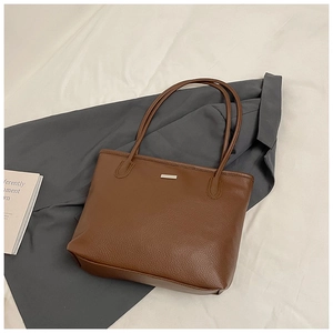 Gros plan du sac cabas en cuir marron à motif litchi avec boucle en métal rectangulaire