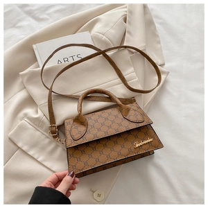 Détail du sac à main marron à motif quadrillé avec logo doré sur un blazer beige chic