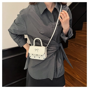 Détail du mini sac à bandoulière blanc avec pois noirs et fermoir papillon argenté