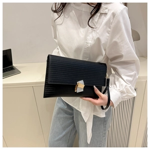 Detail of black textured envelope clutch with gold geometric lock and wrist strap handle