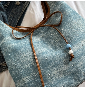 Detail of light blue denim tote with silver rhinestones and brown bow drawstring