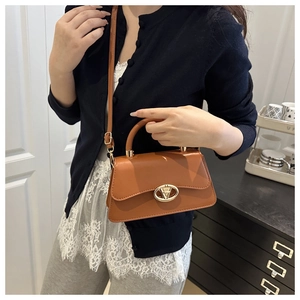 Femme portant un sac bandoulière en cuir caramel avec un fermoir géométrique en V doré