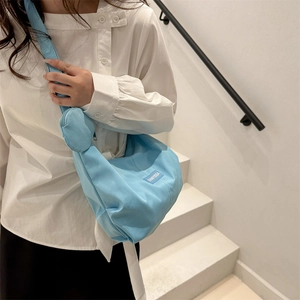 Grand sac bandoulière en nylon bleu clair avec pochette sur un escalier minimaliste