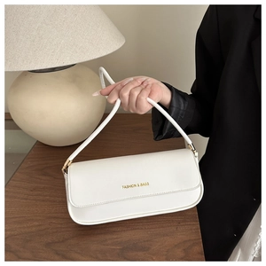 Sac baguette chic blanc crème avec lettrage doré présenté dans un décor élégant