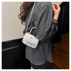 Détail du mini sac bandoulière argenté avec pois rouges et nœud sur le côté