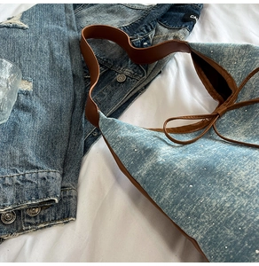 Detail of washed denim tote bag with shiny rhinestones and brown leather shoulder strap