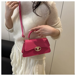 Detail of fuchsia trapezoid bag featuring a golden circular cutout lock and smooth PU leather