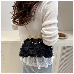 Détail d'un sac de soirée noir à fleurs avec fermoir doré et fine bandoulière chaîne