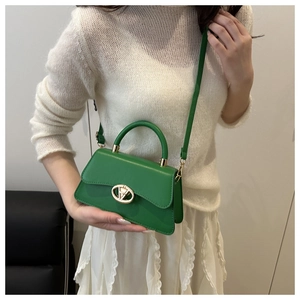Détail du sac à main en cuir vert avec boucle dorée et poignée supérieure structurée