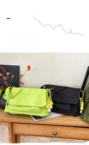 Detail von Nylon-Umhängetaschen in Grün und Schwarz mit Sonnenblumen-Anhänger im Regal