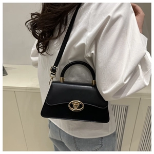 Détail d'un sac à main classique en cuir noir avec fermoir doré en V porté par le mannequin