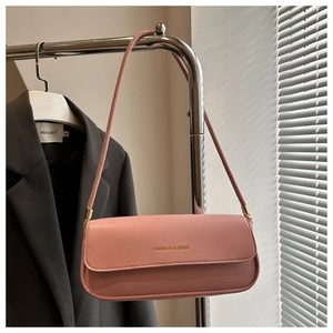 Detail der rosa Baguette-Tasche mit goldener Aufschrift an einem Metallgestell aufgehängt