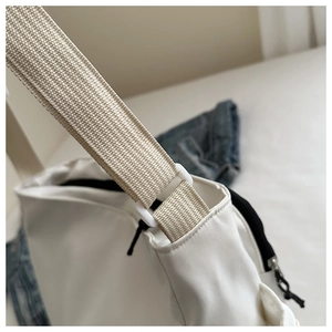 Détail du sac fourre-tout en toile blanche avec bandoulière réglable et zip noir