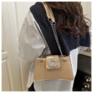 Détail du sac à bandoulière chic avec boucle en cristal et chaîne sur le mannequin