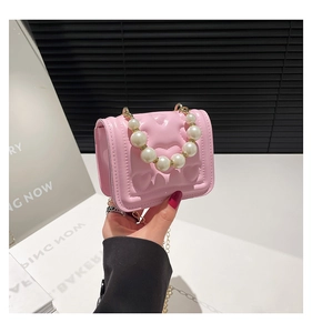 Close-up of pink heart-quilted patent leather bag with large pearl handle and gold chain