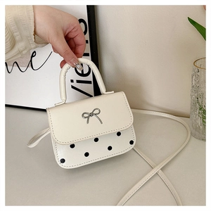 Détail d'un mini sac bandoulière blanc crème à pois noirs avec un nœud argenté chic