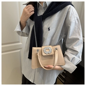 Detail of a beige leather shoulder bag with a large sparkling rhinestone buckle and chain