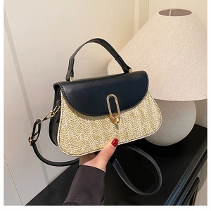 Detail of hand-woven straw crossbody bag with black leather flap and gold metal clasp