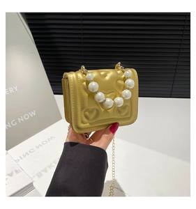 Close-up of gold heart-quilted mini bag with large pearl handle and metal chain strap