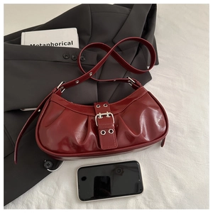 Detail of burgundy glossy leather shoulder bag featuring pleated texture and silver buckle