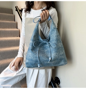 Detail view of blue denim tote bag featuring decorative bow tie and white bead accents