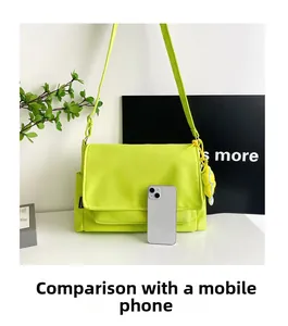 Sac messager en nylon vert fluo avec comparaison de taille par smartphone et breloque