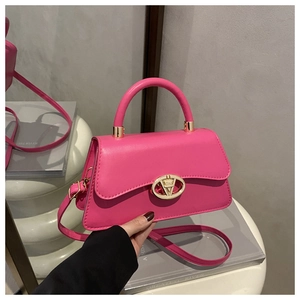 Détail du petit sac carré magenta avec boucle en V dorée et poignée ronde rigide