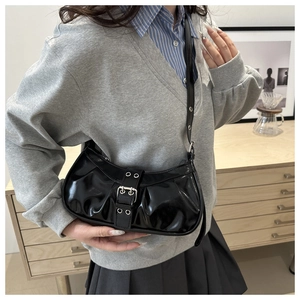 Detail of vintage pleated black patent leather shoulder bag with metallic buckle strap
