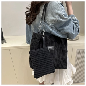 Detail view of black corduroy tote bag with silver chain strap and matching small pouch