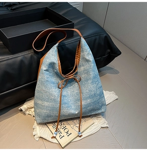 Close-up of blue denim tote bag featuring glittering sequins and brown leather handles