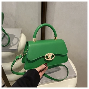 Détail d'un sac à main vert avec fermoir rotatif en V doré et poignée supérieure chic