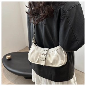 Detail view of cream pleated crescent bag with buckle and studs on a female model