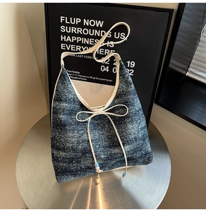 Detail of blue denim tote bag with decorative bow and beads on a metallic stand
