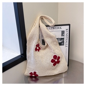 Detail of hand-crocheted tote bag with red floral patterns and openwork knit texture