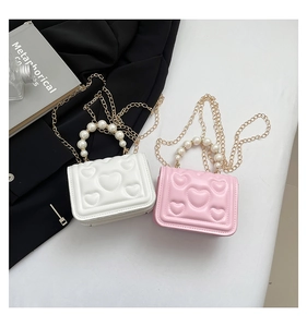 Detail of heart embossed mini bags with pearl handles and golden chain straps