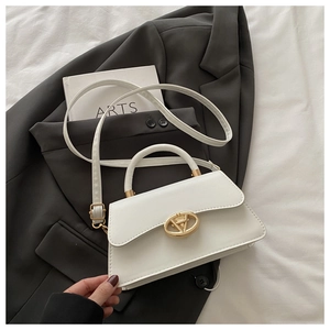 Détail d'un sac à main blanc avec fermoir doré posé sur un blazer gris chic