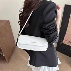 White faux leather rectangular flap shoulder bag worn by model in a black blazer suit