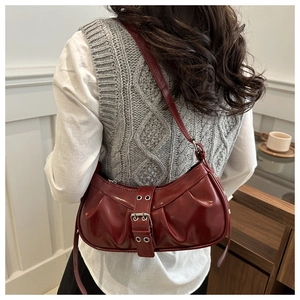 Detail of burgundy leather shoulder bag with vintage pleats and buckle decoration