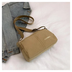 Flat lay of khaki nylon crossbody bag with adjustable strap on white textured background