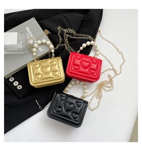 Three mini heart-embossed handbags in gold, red, and black with pearl handles and chains