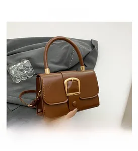 Dettaglio borsa vintage in pelle marrone con grande fibbia a U dorata e tracolla