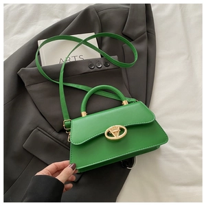 Détail du sac à main vert vif avec fermoir en V doré sur une veste grise