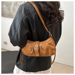Close-up of caramel brown pleated shoulder bag with decorative buckle on a model