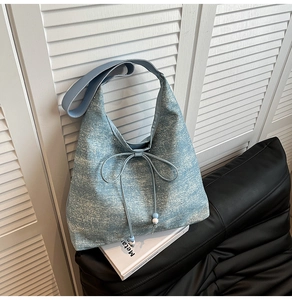Detail of light blue denim tote bag with drawstring bow and decorative beaded accents