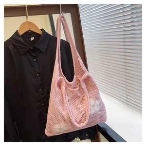 Detail of pink knitted tote bag showing white floral patterns and hollow crochet texture