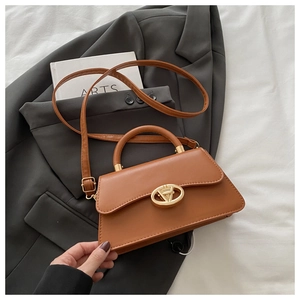 Sac à main en cuir marron avec fermoir tournant doré en V sur une veste grise