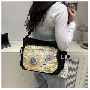 Détail du sac ita noir avec fenêtre transparente, volants jaunes et décoration de nœud blanc