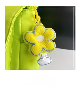 Vue rapprochée du charm fleur en peluche jaune avec couture bleue sur sac en toile verte